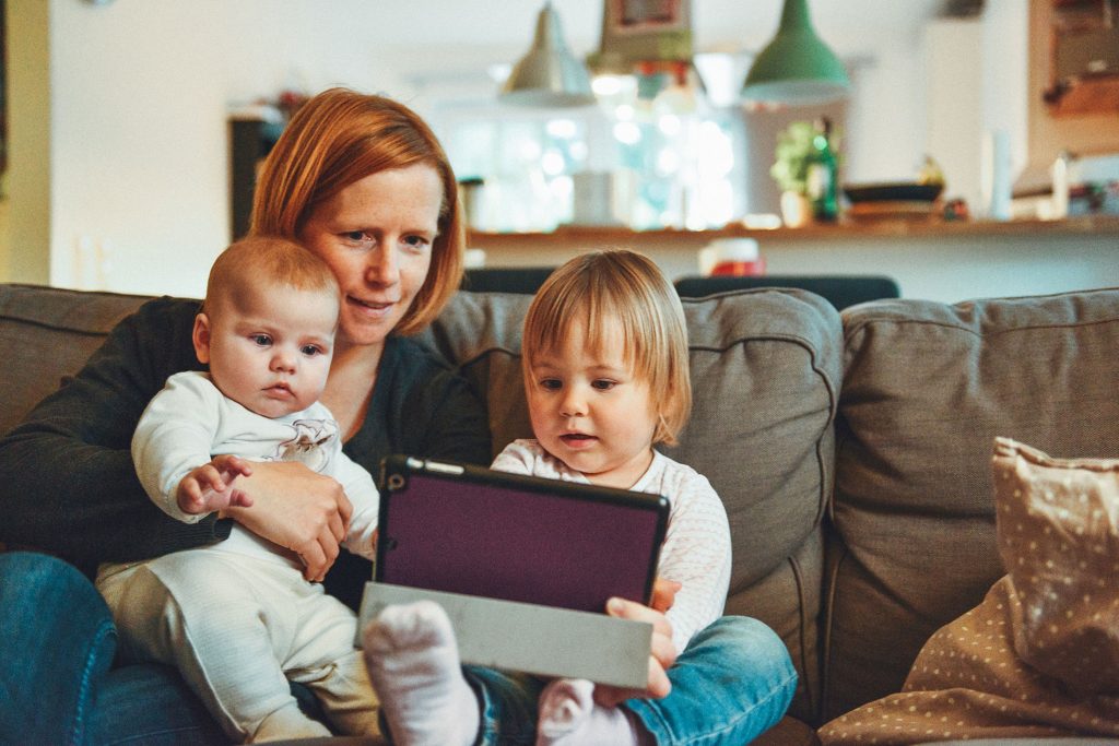 Mom with two kids on couch playing with tablet